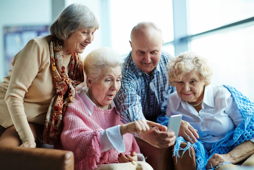 Four senior friends look surprised while talking on the phone.