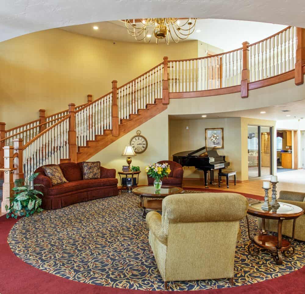Lobby with a grand staircase, high ceilings and ample seating at senior living community in Green Bay, Wisconsin.