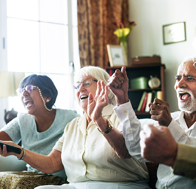 Friends cheering on a couch while watching the big game.