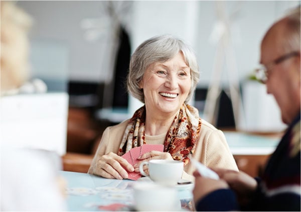 Senior woman smiling and enjoying coffee with friends at a table