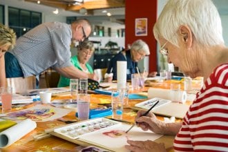 Group of seniors paint with help of instructor as a form of therapy