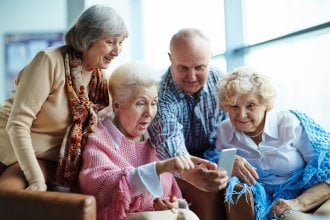 Four senior friends look surprised while talking on the phone.