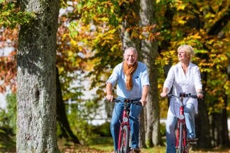 Seniors enjoying a bike ride during the Fall with orange and yellow leaves on the trees.