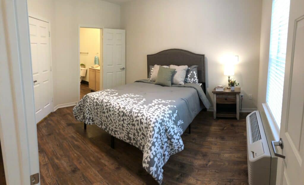 Queen-sized bed in a senior apartment at The Waterford on Highland Colony, a senior living community located in Ridgeland, Mississippi.