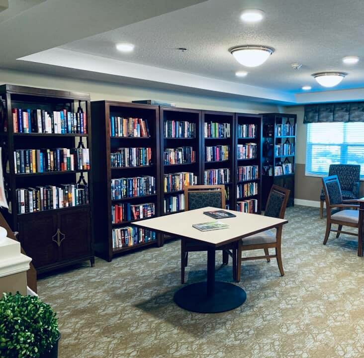 Library inside The Harrison, a senior community in Indianapolis, Indiana with rows of books and ample seating.