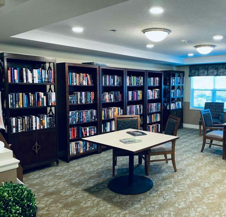 Library inside The Harrison, a senior community in Indianapolis, Indiana with rows of books and ample seating.