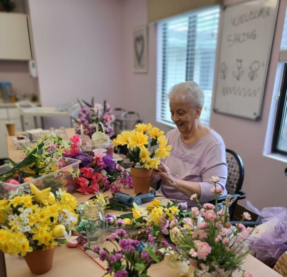 senior woman smiles while putting a flower bouquet together