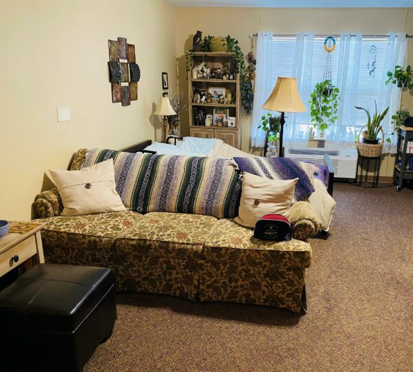 Apartment living space with a couch and small bed behind at a senior living community in Indianapolis, Indiana.