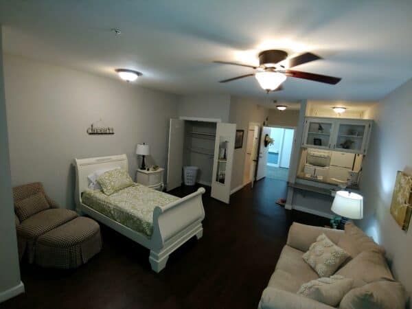 Studio apartment with lounge area, dining area, large bed and kitchenette at a senior living facility in Conroe, Texas.