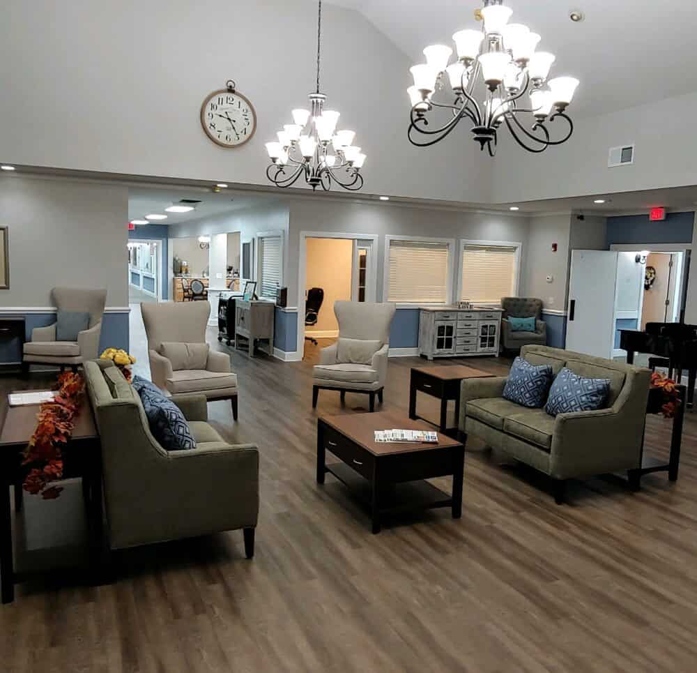 Lounge area with piano, chandeliers and ample seating at a senior living facility in Conroe, Texas.