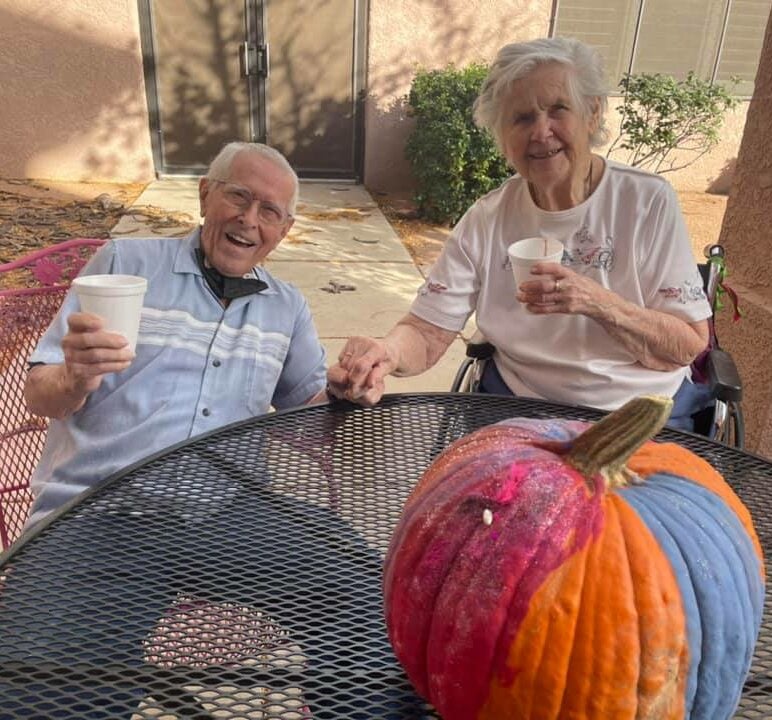 senior man and senior woman sit outside with their drinks