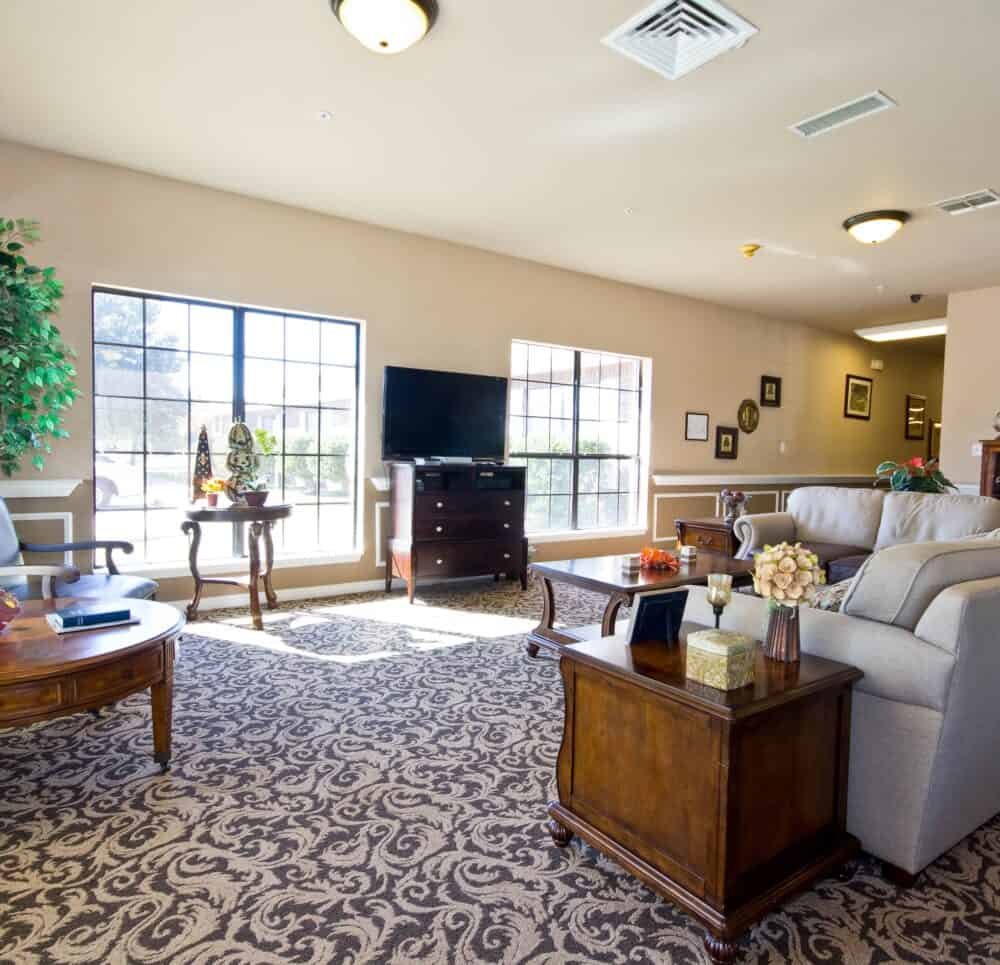 Lounge area with comfortable seating and TV at a senior living community in College Station, Texas.