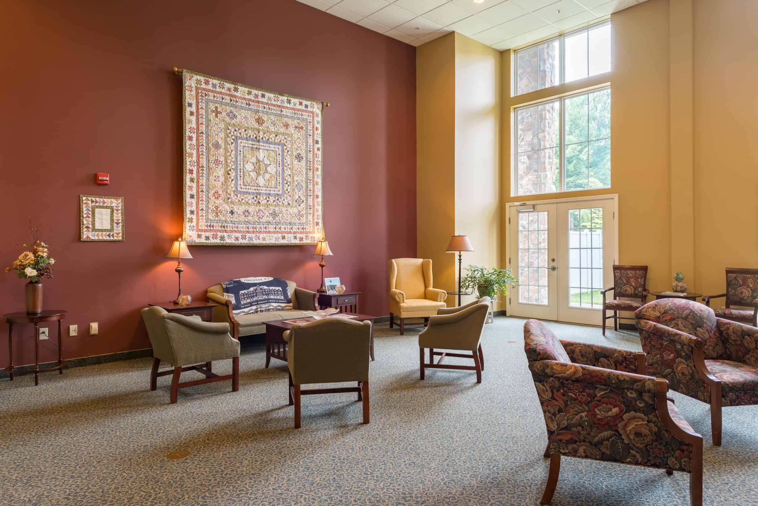 Large seating area in the lobby of a senior living community in Oneonta, New York with chairs and couches.