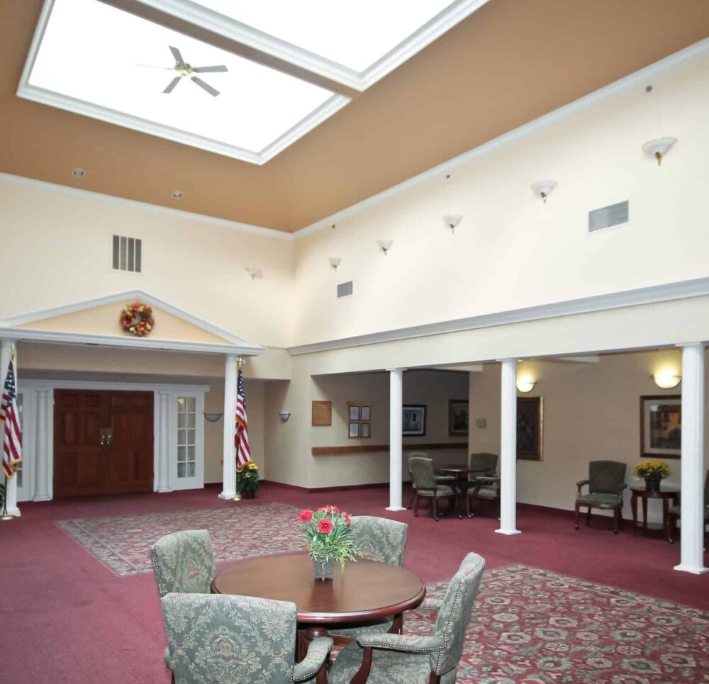 Lobby and lounge area at a senior living facility complete with table and chairs and large ceilings in Williamsville, New York.