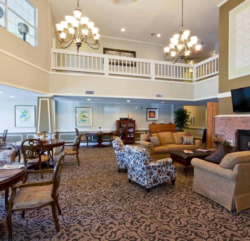 Lounge area at a senior living community in Conroe, Texas with couches, television and fireplace.