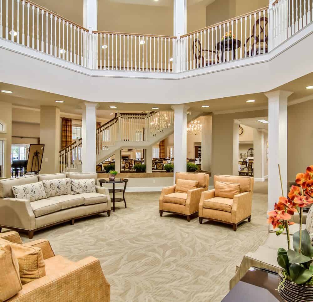 Main lobby and entrance with couches and grand staircase at a senior living community in San Antonio, Texas.