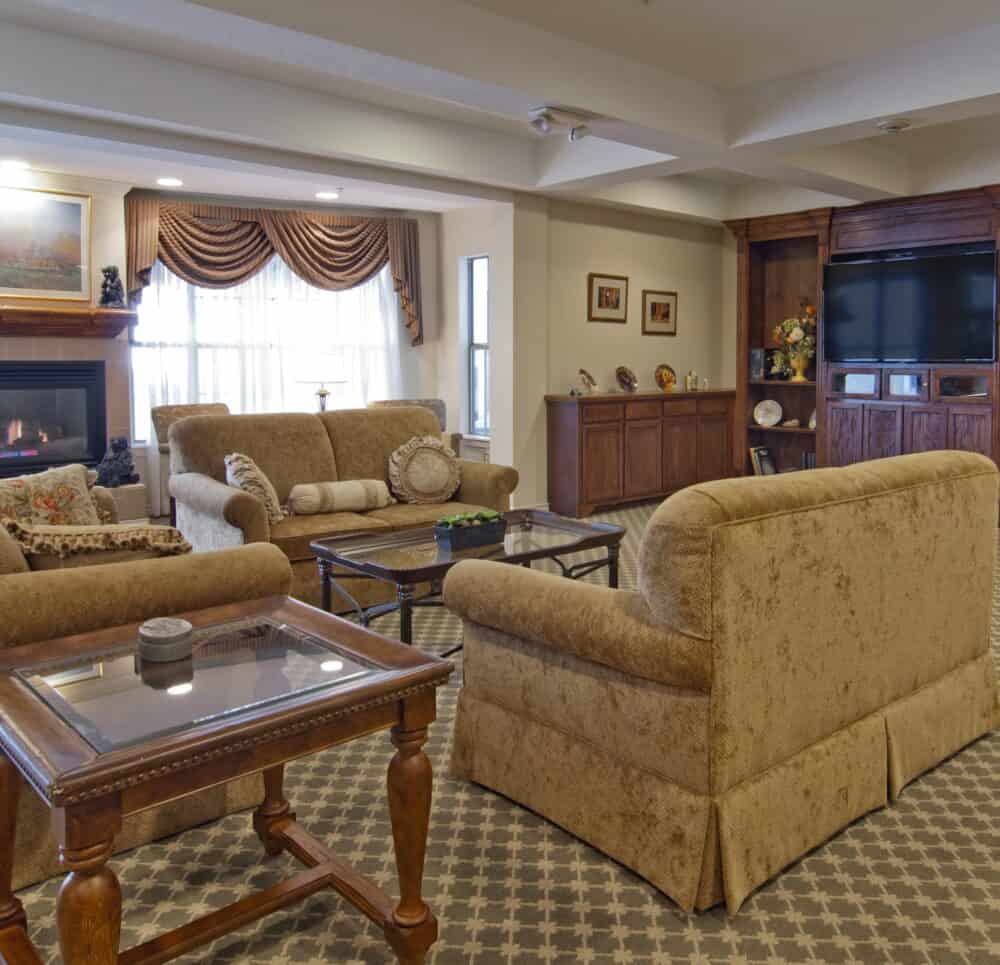 A large lounge area with couches, fireplace and television at senior living community in Irving, Texas.