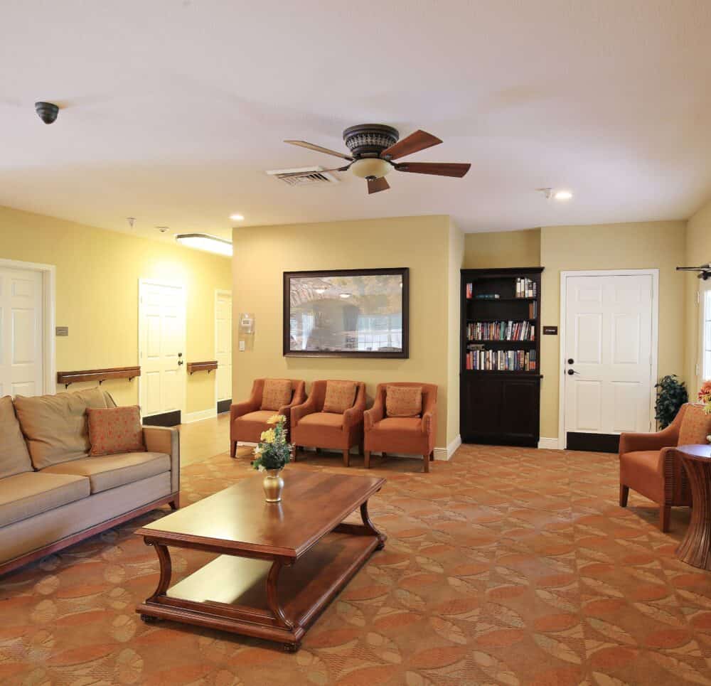 Lounge area at a memory care community in Pensacola, Florida with a TV and comfortable seating.