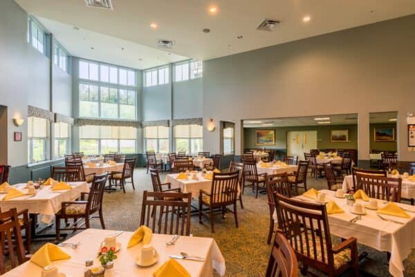 Dining room area at a senior living community in Oneonta, New York with tons of natural light and ample seating.