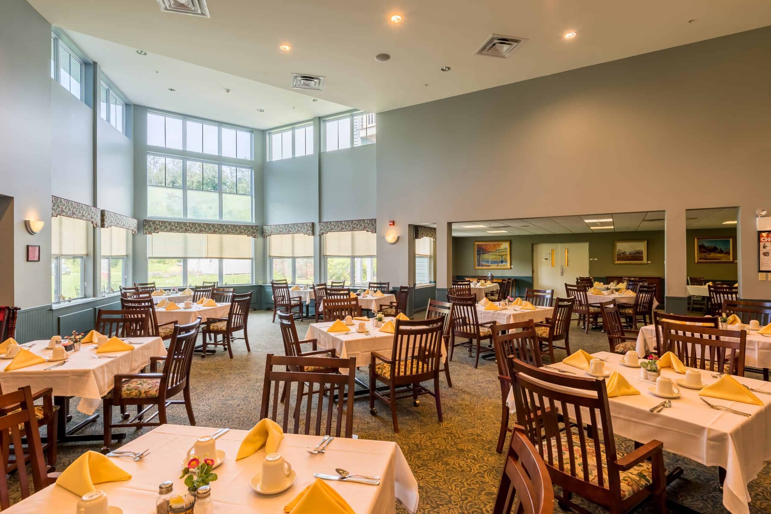 Dining room area at a senior living community in Oneonta, New York with tons of natural light and ample seating.