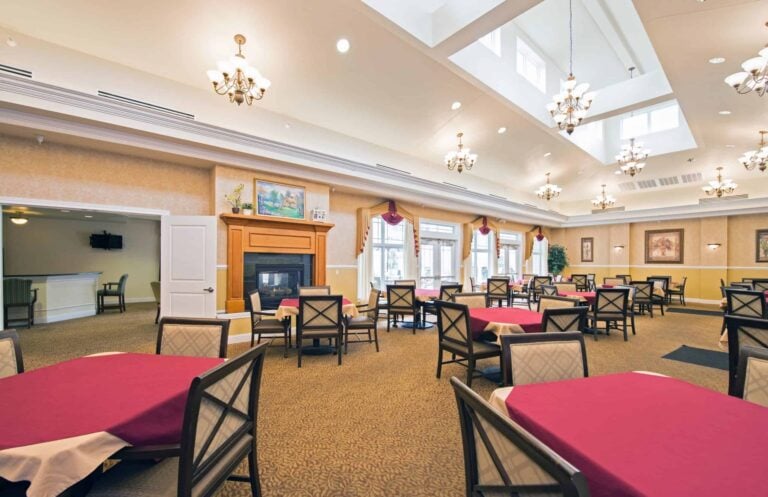 Dining room at a senior living community in Dayton, Ohio with ample natural light, plenty of seating and a fireplace.