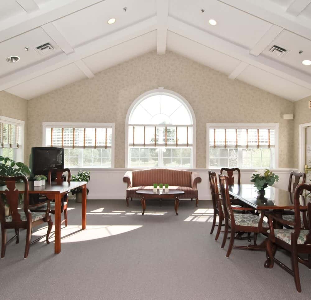 Whispering Pines senior living community living room area with large windows in Columbiana, Ohio.