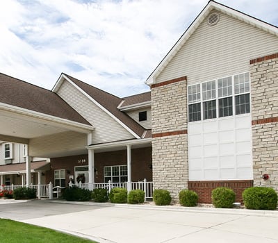 Front entrance to senior living community in St. Joseph, Missouri with light stone work and white railing.