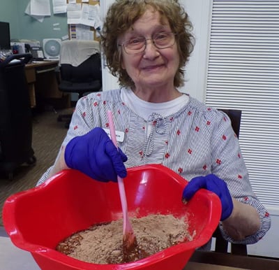 Resident smiling and mixing brownies from scratch in a large bowl in Mansfield, Ohio.