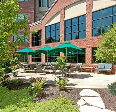 Large patio with umbrella covered tables overlooking a landscaped courtyard in Cincinnati, Ohio.