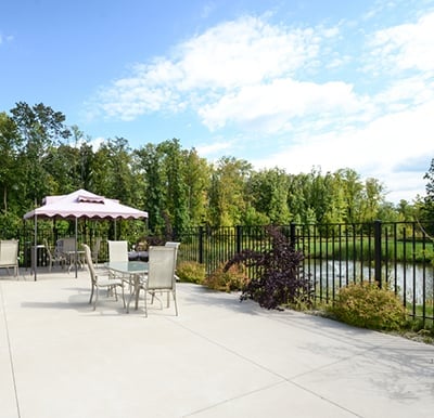 Large fenced-in patio with outdoor tables and chairs overlooking a pond in Plymouth, Wisconsin.