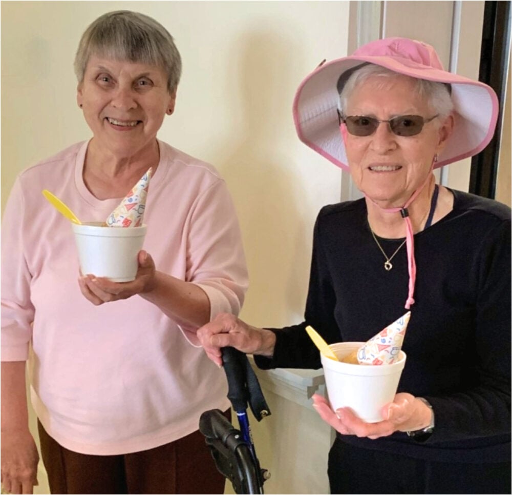 Two older women smile while holding a frozen treat at their senior living community in Batesville, Indiana.