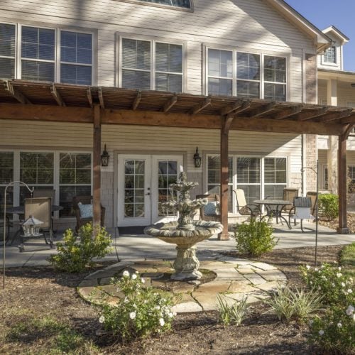 Outdoor courtyard at senior living community with a water fountain, seating and trees in Conroe, Texas