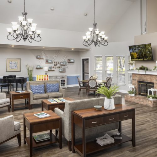 Lounge area with a piano, chandeliers and ample seating at a senior living facility in Conroe, Texas