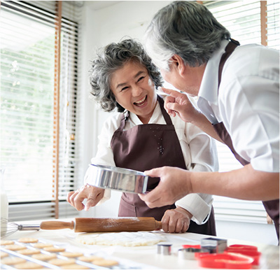 Senior man and woman laughing while making cookies.