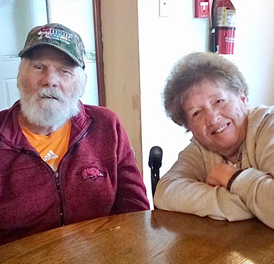 senior man and senior woman smile together while seated at a table