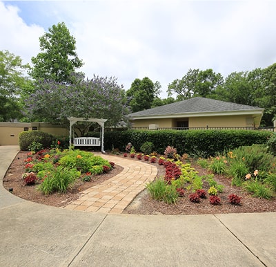 Beautifully landscaped garden area with a porch swing and walking path in Pensacola, Florida.