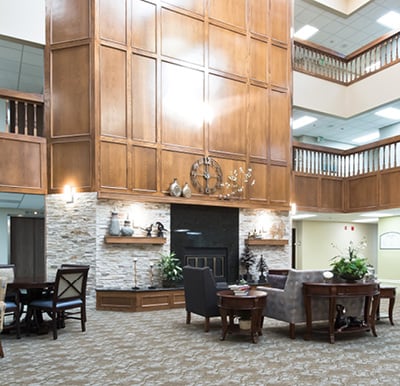 Grand fireplace surrounded by rich wood paneling in a large atrium with comfortable lounge seating in Omaha, Nebraska.