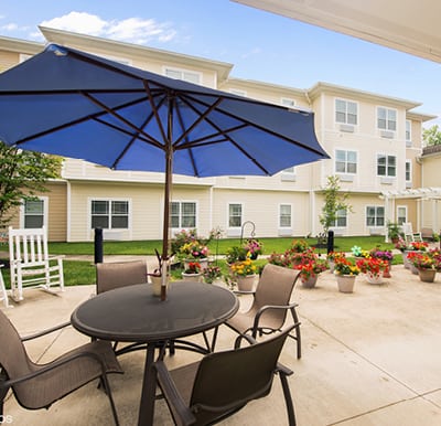 Large patio in courtyard with umbrella covered tables and a walking path.