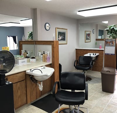 Beauty salon with many salon chairs, a hair washing sink and mirrors.