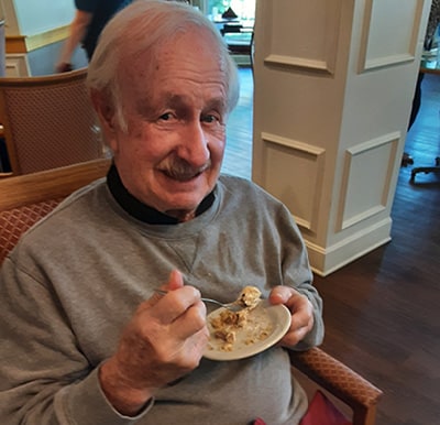 A resident smiling and eating a plate of dessert in Hamilton, Ohio.