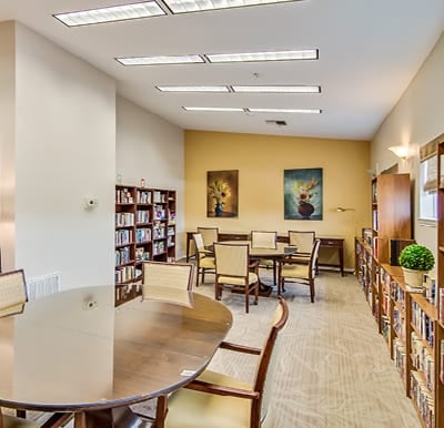 Library with wall-to-wall bookshelves, a lounge seating area and multiple tables with chairs in San Antonio, Texas.