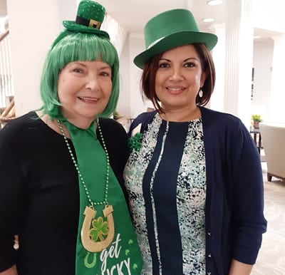 A senior living resident with a staff member wearing St. Patrick’s day outfits in San Antonio, Texas.