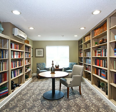 Well-stocked library with bookshelves covering two walls and tables with chairs in the center of the room in Columbus, North Carolina.