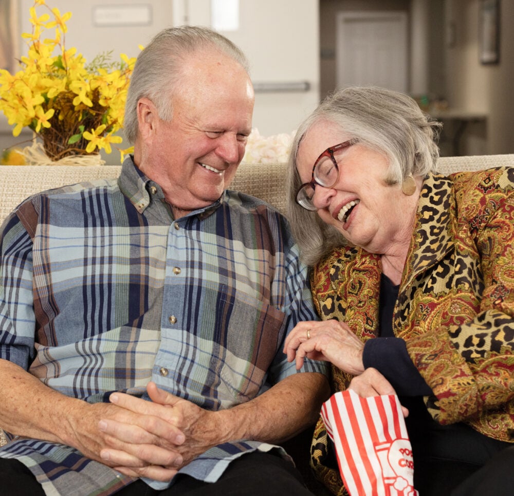 Senior couple laughing and eating popcorn