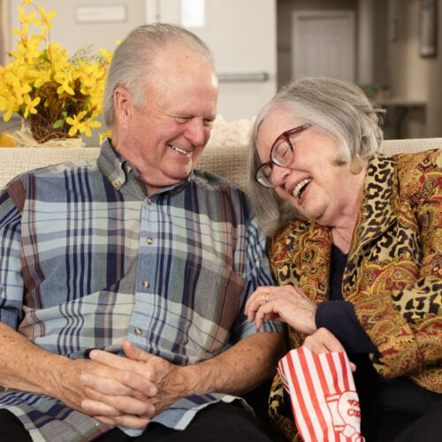 Senior couple laughing and eating popcorn