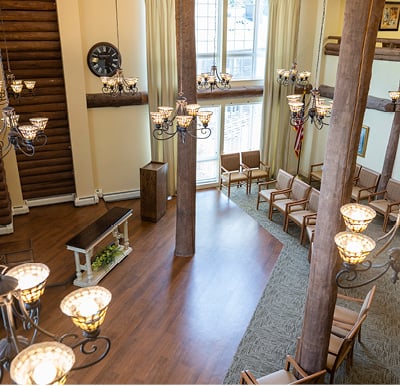 Senior living community room with floor to ceiling windows, plenty of seating, a piano and dance floor and elevated stage area in the corner in Maple Grove, Minnesota.