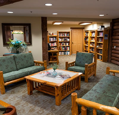 Library room in loft area of senior living community with a log-cabin style table and chairs and wooden bookcases in Maplel Grove, Minnesota.