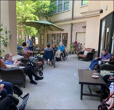 Senior citizens sitting in a courtyard at their assisted living and memory care community in Humble, Texas.