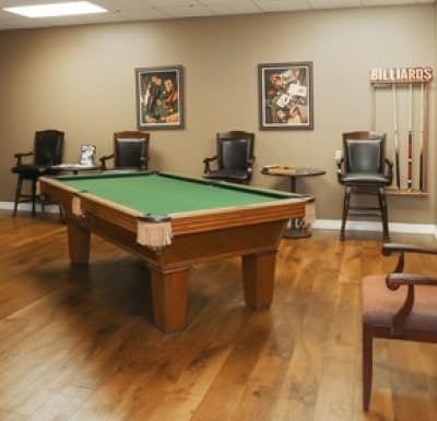 A billiards table in a large room with many chairs.
