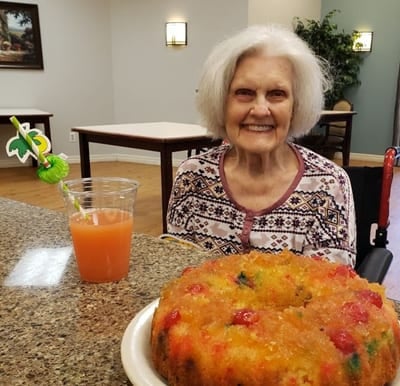 A senior woman smiling and enjoying a drink and dessert in Humble, Texas.